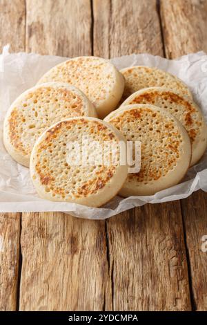 Gros plan de crumpets anglais fraîchement préparés sur du papier parchemin sur la table. Vertical Banque D'Images