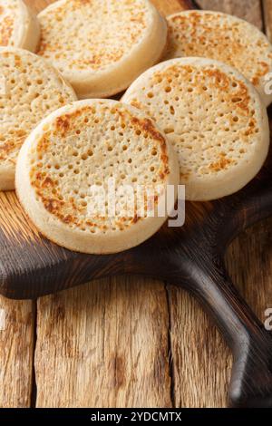 Crumpets frais d'un gros plan de boulangerie sur la planche de bois sur la table. Vertical Banque D'Images