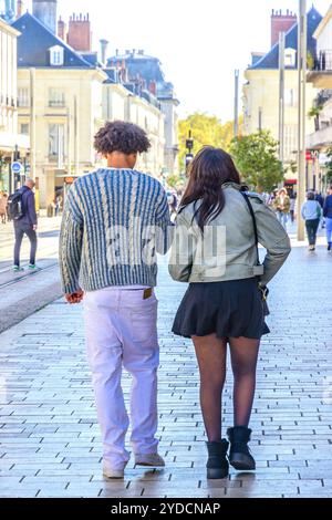 Vue arrière d'un jeune couple ethnique marchant le long du trottoir du centre-ville - Tours, Indre-et-Loire (37), France. Banque D'Images