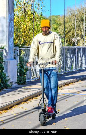 Homme sur scooter électrique traversant le pont suspendu non-trafic - Tours, Indre-et-Loire (37), France. Banque D'Images