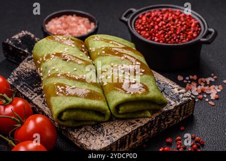 Crêpes aux épinards farcies au poulet, champignons, sel et épices sur fond de béton foncé Banque D'Images