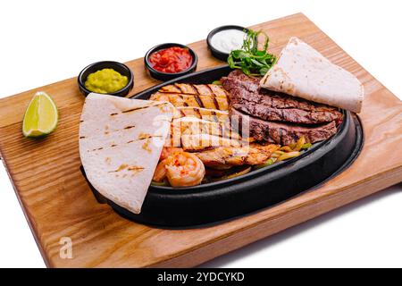 Poulet au bœuf et fajitas aux crevettes sur une assiette grésillante en fonte de fer Banque D'Images