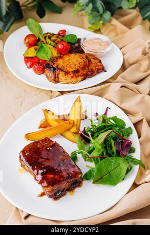 Côtes de porc avec pommes de terre et steak de porc avec légumes grillés Banque D'Images