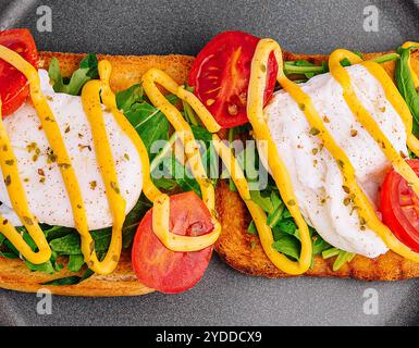 Oeuf poché avec roquette, tomates cerises et pain grillé Banque D'Images