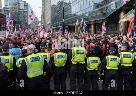 Westminster, Londres, Royaume-Uni. 26 octobre 2024. Les partisans de Stephen Yaxley-Lennon (alias Tommy Robinson) se rassemblent dans Victoria Street pour une marche de protestation vers Whitehall. Les thèmes de la manifestation incluent l'immigration, et une manifestation d'opposition organisée par Stand Up to Racism est prévue pour marcher à l'autre bout de Whitehall. La police métropolitaine et les unités recrutées d'ailleurs participent en nombre à la lutte contre la violence. Cordon de police retenant les manifestants dans la rue Victoria Banque D'Images