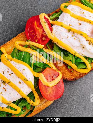 Oeuf poché avec roquette, tomates cerises et pain grillé Banque D'Images