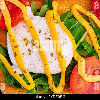 Oeuf poché avec roquette, tomates cerises et pain grillé Banque D'Images