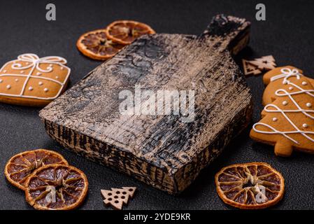 Planche à découper en bois vide avec espace de copie avec des biscuits en pain d'épice et décor de Noël sur fond de texture sombre Banque D'Images