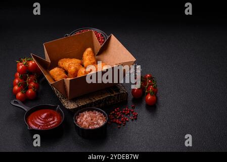 Camembert pané ou fromage brie cuit sous forme de pépites avec du sel et des épices sur un fond de béton foncé Banque D'Images