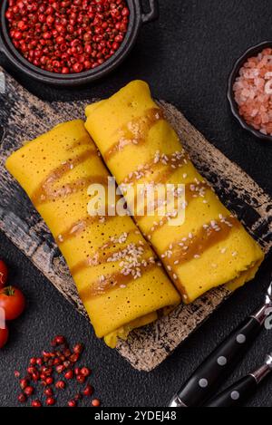 Crêpe sucrée ou salée avec différentes garnitures pour un petit déjeuner copieux sur un fond de béton foncé Banque D'Images