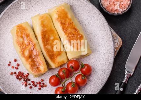 Crêpe sucrée ou salée avec différentes garnitures pour un petit déjeuner copieux sur un fond de béton foncé Banque D'Images