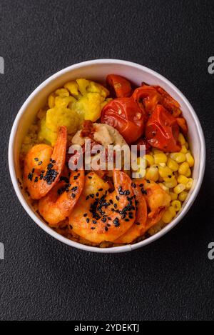 Crevettes tigrées bouillies avec du porridge, des tomates et du maïs sur un fond de béton foncé Banque D'Images