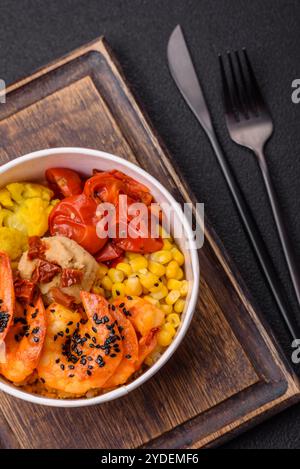 Crevettes tigrées bouillies avec du porridge, des tomates et du maïs sur un fond de béton foncé Banque D'Images