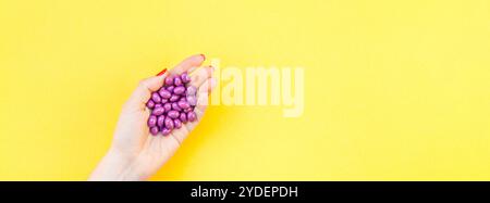 Main de femme tenant des pilules violettes poignée Banque D'Images