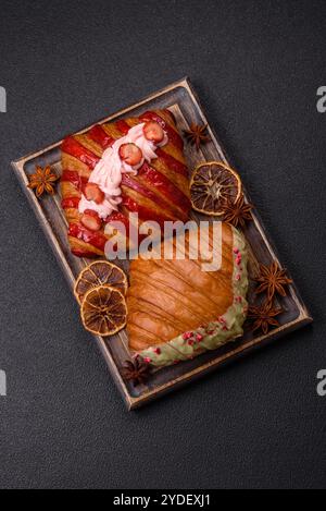 Croissant rouge sucré croustillant à la pistache, à la framboise et à la fraise sur un fond de béton foncé Banque D'Images