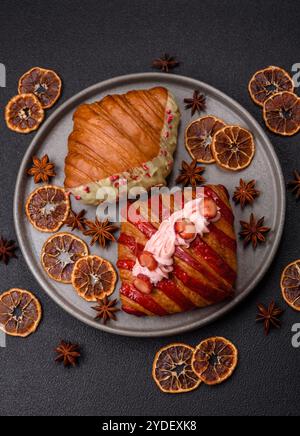 Croissant rouge sucré croustillant à la pistache, à la framboise et à la fraise sur un fond de béton foncé Banque D'Images