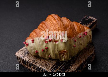 Croissant rouge sucré croustillant à la pistache, à la framboise et à la fraise sur un fond de béton foncé Banque D'Images