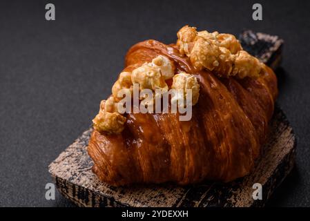 Croissant croustillant sucré avec caramel salé et pop-corn glacé sur un fond texturé foncé Banque D'Images