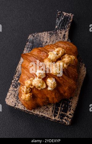 Croissant croustillant sucré avec caramel salé et pop-corn glacé sur un fond texturé foncé Banque D'Images