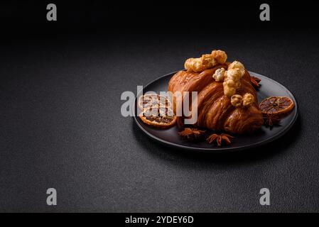 Croissant croustillant sucré avec caramel salé et pop-corn glacé sur un fond texturé foncé Banque D'Images