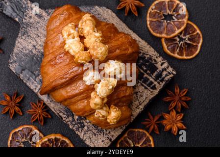 Croissant croustillant sucré avec caramel salé et pop-corn glacé sur un fond texturé foncé Banque D'Images