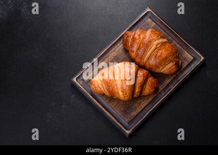 Délicieux croissants frais et croustillants sur fond de béton sombre.Petit déjeuner savoureux Banque D'Images