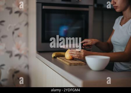 Femme préparant une salade de fruits saine dans une cuisine moderne Banque D'Images