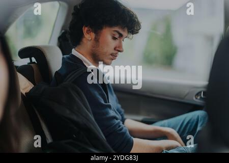 Parent déposant son fils adolescent à l'école en voiture Banque D'Images