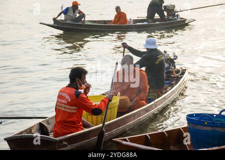 Thaïlande. 25 octobre 2024. Une vue d'un moine assis sur un bateau en bois qui attend le départ, avec son chauffeur fumant une cigarette, sur la rive de la rivière Chao Phraya. La tradition de donner l'aumône à une centaine de moines à Pathum Thani, en Thaïlande, est une cérémonie bouddhiste vieille de plusieurs siècles qui se tient le long des rivières et des canaux après la fin du Carême bouddhiste. Les moines se rassemblent dans des bateaux pour recevoir des offrandes des habitants, qui préparent la nourriture et participent à la création de mérite. Cet événement célèbre la communauté, la foi et le patrimoine culturel. Crédit : SOPA images Limited/Alamy Live News Banque D'Images