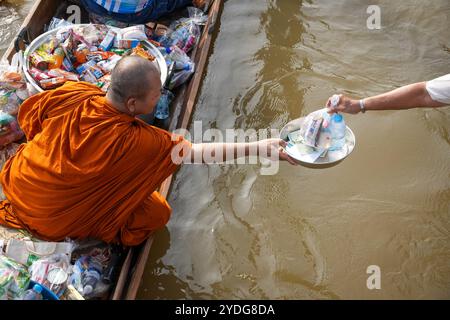 Thaïlande. 25 octobre 2024. Un moine qui est assis dans une barque est vu tenant sa main pour recevoir des offrandes, sur la rivière Chao Phraya. La tradition de donner l'aumône à une centaine de moines à Pathum Thani, en Thaïlande, est une cérémonie bouddhiste vieille de plusieurs siècles qui se tient le long des rivières et des canaux après la fin du Carême bouddhiste. Les moines se rassemblent dans des bateaux pour recevoir des offrandes des habitants, qui préparent la nourriture et participent à la création de mérite. Cet événement célèbre la communauté, la foi et le patrimoine culturel. Crédit : SOPA images Limited/Alamy Live News Banque D'Images