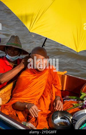 Thaïlande. 25 octobre 2024. Portrait d'un moine souriant sous un parapluie, assis sur un bateau avec son bol d'aumônes, sur la rivière Chao Phraya. La tradition de donner l'aumône à une centaine de moines à Pathum Thani, en Thaïlande, est une cérémonie bouddhiste vieille de plusieurs siècles qui se tient le long des rivières et des canaux après la fin du Carême bouddhiste. Les moines se rassemblent dans des bateaux pour recevoir des offrandes des habitants, qui préparent la nourriture et participent à la création de mérite. Cet événement célèbre la communauté, la foi et le patrimoine culturel. Crédit : SOPA images Limited/Alamy Live News Banque D'Images