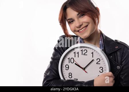 Une jeune femme souriante tenant avec enthousiasme une horloge dans sa tenue élégante, Radiating Joy Banque D'Images