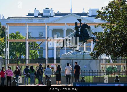 Washington, États-Unis. 25 octobre 2024. Les passants se tiennent devant une clôture sur le terrain de la Maison Blanche. Les premiers préparatifs de construction pour les élections sont en cours dans la zone bouclée derrière le mémorial équestre. La statue doit représenter l'ancien président américain Andrew Jackson. Crédit : Soeren Stache/dpa/Alamy Live News Banque D'Images