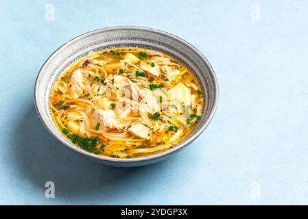 Soupe de nouilles au poulet maison sur fond bleu. Bol de soupe chaude au poulet, nourriture saine et réconfortante. Banque D'Images