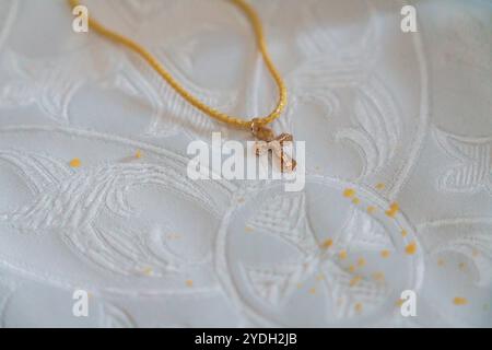 Collier de croix en or élégant sur fond de tissu complexe. Banque D'Images