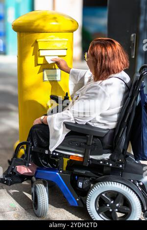 Service postal accessible : utilisateur en fauteuil roulant affichant une lettre Banque D'Images