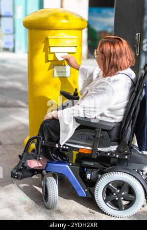 Service postal accessible : utilisateur en fauteuil roulant affichant une lettre Banque D'Images