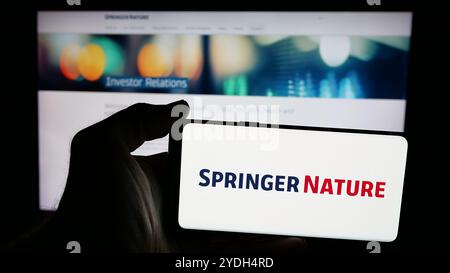 Personne tenant un smartphone avec le logo de la société d'édition académique Springer nature sur l'écran en face du site Web. Concentrez-vous sur l'affichage du téléphone. Banque D'Images