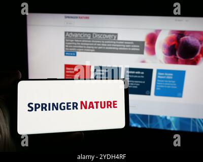 Personne tenant le téléphone portable avec le logo de la société d'édition académique Springer nature sur l'écran en face de la page Web. Concentrez-vous sur l'affichage du téléphone. Banque D'Images