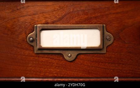 Une étiquette blanche vierge dans un vieux support en laiton sur Un tiroir de classeur en bois Vintage Banque D'Images