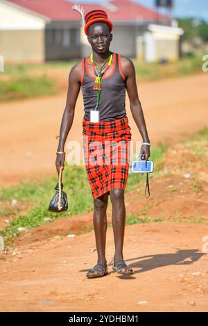 Moderne et ancien. Un homme de Karimojong en tenue traditionnelle se déplace avec un téléphone portable fixé sur un stand de selfie à Kotido, Karamoja Ouganda. Banque D'Images