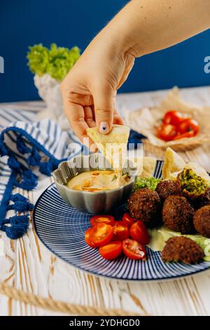 Tremper à la main le pain pita dans le houmous crémeux. Expérience de collation parfaite au moyen-Orient Banque D'Images