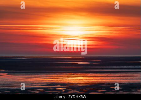 Coucher de soleil rouge sur une plage vide à Baie de somme, France, soleil caché derrière les nuages Banque D'Images