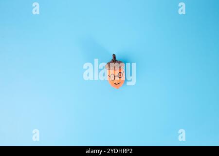 peint en gland orange avec un chapeau marron sur un fond bleu clair uni. La simplicité et le minimalisme, étape dans le processus créatif, bricolage, tuteur Banque D'Images