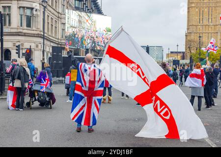 Londres, Royaume-Uni. 26 OCT, 2024. Un homme portant l'Union Jack agite le drapeau de la croix de Saint Georges alors que des milliers de personnes se rassemblaient pour le rassemblement Unite the Kingdom organisé par Tommy Robinson, qui n'était pas présent en raison de sa détention en prison, rassemblant à Victoria la marche s'est pacifiquement dirigée vers la place du Parlement où un nouveau documentaire « Lawfare » a été projeté. Stand Up to Racism a mobilisé une contre-protestation avec des milliers de personnes, qui se sont rassemblées pacifiquement à l'autre bout de whitehall. Crédit Milo Chandler/Alamy Live News Banque D'Images