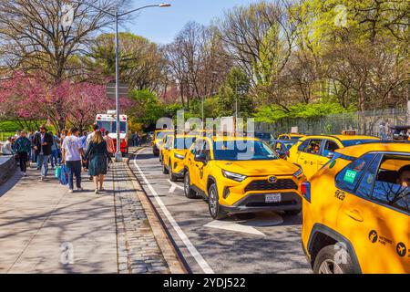 Des taxis jaunes faisaient la queue près de Central Park, New York, et les piétons se promenaient le long d'un sentier aux couleurs printanières. New York. ÉTATS-UNIS. Banque D'Images