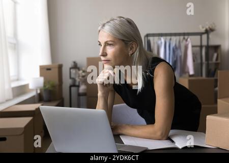 Femme d'affaires âgée sérieuse regarder loin distrait de l'ordinateur portable Banque D'Images