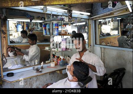 08.12.2011, Mumbai, Maharashtra, Inde, Asie, un barbier rase un client dans un petit salon pour hommes dans le bidonville de Dharavi à Mumbai, en Asie Banque D'Images