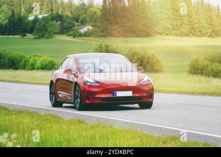 Red Tesla Model 3 berline voiture électrique année 2020 à grande vitesse sur l'autoroute. Ajout du filtrage dans post prod. Salo, Finlande. 23 juin 2022 Banque D'Images