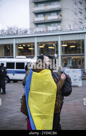 24.02.2023, Berlin, Allemagne, Europe, trois participants se tiennent fermement embrassés devant le Café Moskau, qui a été brièvement rebaptisé Café Kiev, devant o Banque D'Images